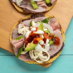 Corn toast with ham and Oaxaca cheese on turquoise background. Mexican food