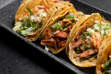 Pork tacos called al pastor with pineapple on dark background. Mexican tacos