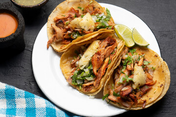 Pork tacos called al pastor with pineapple on dark background. Mexican tacos