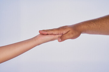 Mano de hombre adulto latino haciendo un gesto con la mano de un niño en un fondo blanco