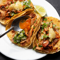 Pork tacos called al pastor with pineapple on dark background. Mexican tacos