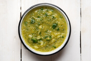 Mexican piquant green sauce with cilantro and onion on white background