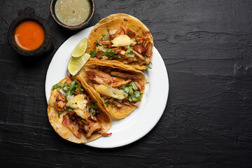 Pork tacos called al pastor with pineapple on dark background. Mexican tacos