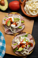 Corn toast with ham and Oaxaca cheese on dark background. Mexican food