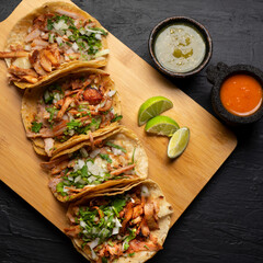 Pork tacos called al pastor with pineapple on dark background. Mexican tacos