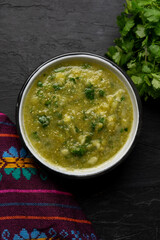 Mexican piquant green sauce with cilantro and onion on dark background