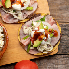 Corn toast with ham and Oaxaca cheese on wooden background. Mexican food