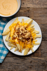 Animal style fries with cheese and caramelized onion on wooden background