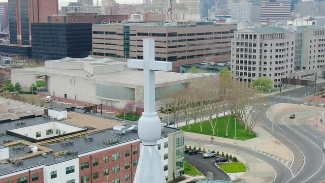 Aerial view around a church cross, with city street background - circling, drone shot