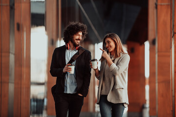 Business man and business woman talking and holding luggage traveling on a business trip, carrying fresh coffee in their hands.Business concept