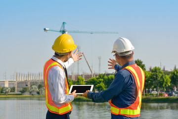 Two Engineer teamwork working tablet technology survey on site construction