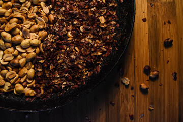 Top view of the process of peeling roasted peanuts in a traditional way. Rustic bamboo background. Hadcraft, organic food texture. traditional latin appetizer.