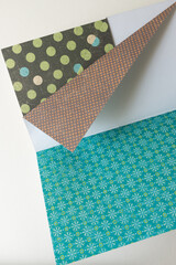 open scrapbooking paper sampler, featuring dots and patterns in dark green, brown orange, and green blue - backgrounds - photo graphed from above with ambient daylight - space for text