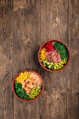 Two bowls of hawaiian poke mix with tuna fish and shrimp on wooden background