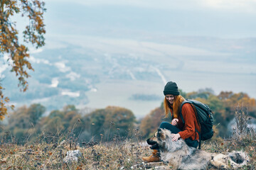 woman hiker admires nature in the mountains next to the dog friendship