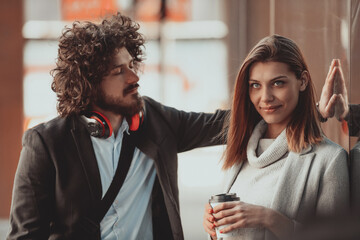 Two serious businessmen drinking coffee to take away. Man and middle-aged woman in official shirt standing outside. Coffee break concept