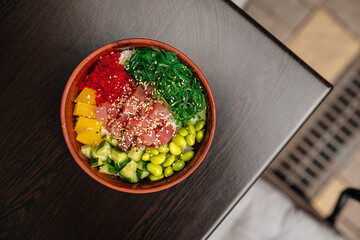 Hawaiian tuna poke bowl with vegetables on wooden table
