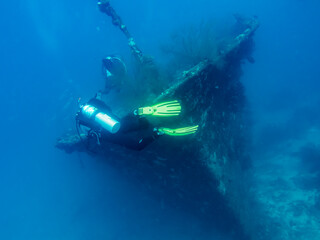 Blurred silhouettes of divers near a sunken ship at the bottom of the Indian Ocean