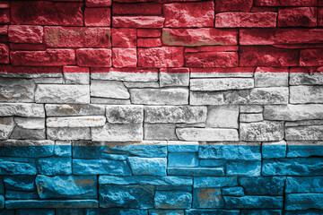 Fototapeta premium National flag of Luxembourg on stone wall background.The concept of national pride and symbol of the country. Flag banner on stone texture background.