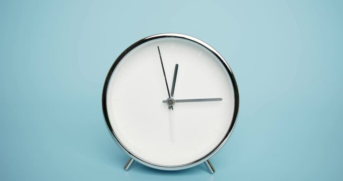 Glittering silver clock isolated on blue background, Time starts walking at 12 o'clock, Time lapse 3 hour.