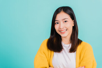 Fototapeta premium Young Asian beautiful woman smiling wear silicone orthodontic retainers on teeth with crossed arms, studio isolated on blue background, retaining tools after removable braces. Dental hygiene concept