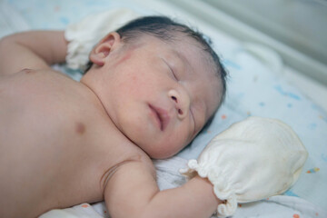 Close up of Asian newborn baby in the delivery room at hospital. In the newborn incubator is A medical device used to regulate the temperature of a newborn baby to be healthy according to the criteria