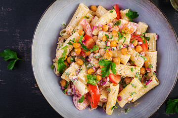 Vegetarian vegetable pasta. Pasta rigatoni with tomato, red onion, parsley and fried chickpeas with nut sauce. Vegan food. Top view, overhead