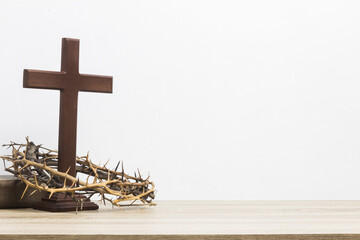 A wooden cross with thorn crown on table.