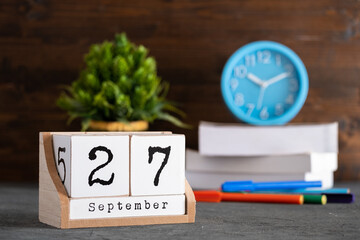 September 27th. September 27 wooden cube calendar with blur objects on background.