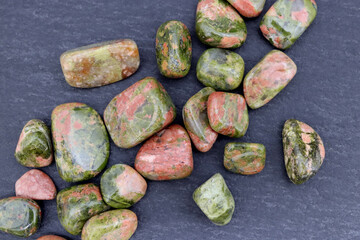 Unakite heap up jewel stones texture on black stone background © Aleksander