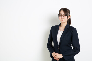 両手を前に添えて笑っているメガネのビジネスウーマン