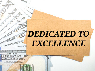 Business concept.Text DEDICATED TO EXCELLENCE with banknote on white background.