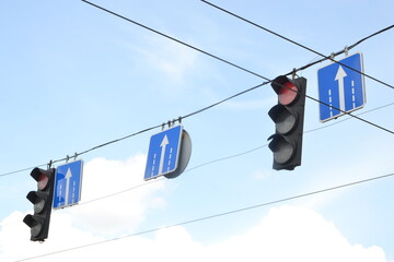 Two traffic lights at intersection on street against blue sky on street, turned on red light means stop for driverless vehicle. Traffic signals concept