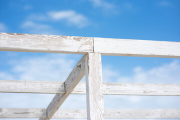 Frame of a beach canopy made of wooden slats, against a background of blue sky