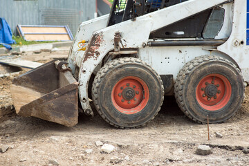 Fototapeta premium Mini excavator at a construction site loads the ground with a front bucket, close-up