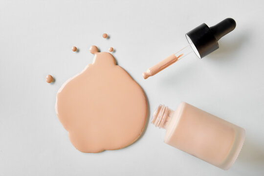 Mockup glass bottle of correction cosmetic product with pipette. Spilled Liquid foundation. Beauty branding concept