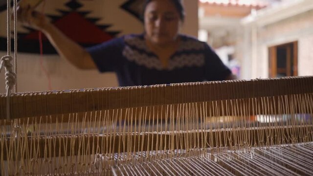 Mexican artisan jobs. woman using a hand weaving loom to elaborate traditional fabric.