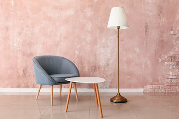 Armchair, table and stylish lamp near color wall in room