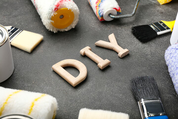 Fototapeta premium Frame made of painter's tools and word DIY on dark background, closeup