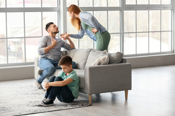 Sad little boy and his quarrelling parents at home