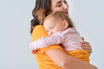 Happy woman and her little daughter on light background