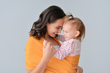 Happy woman and her little daughter on light background