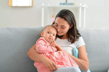 Happy woman and her little daughter sitting on sofa at home