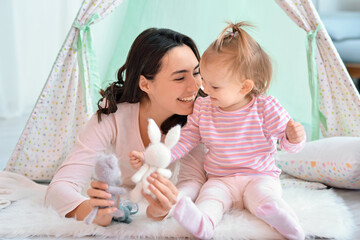 Happy woman and her little daughter playing in wigwam at home © Pixel-Shot
