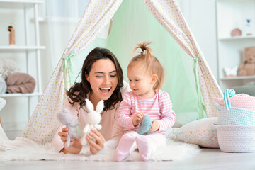 Happy woman and her little daughter playing in wigwam at home © Pixel-Shot
