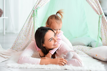 Happy woman and her little daughter playing in wigwam at home © Pixel-Shot