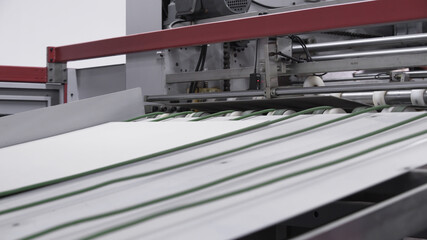 Enterprise for the production of cardboard containers .Cardboard manufacturing layering rollers roll industrial industry printing packaging material closeup. Paper corrugated box factory.