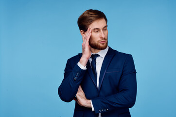 business man in a suit holds his hand near his head displeasure blue background