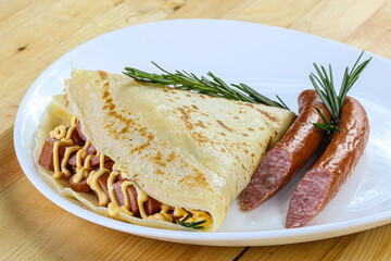 Pancake with sliced sausage and mustard