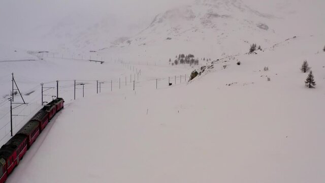 Drone camera flying over amazing mountains during cold season, aerial overlooking of nature environment with locomotiv transport crossing snowy environment during winter